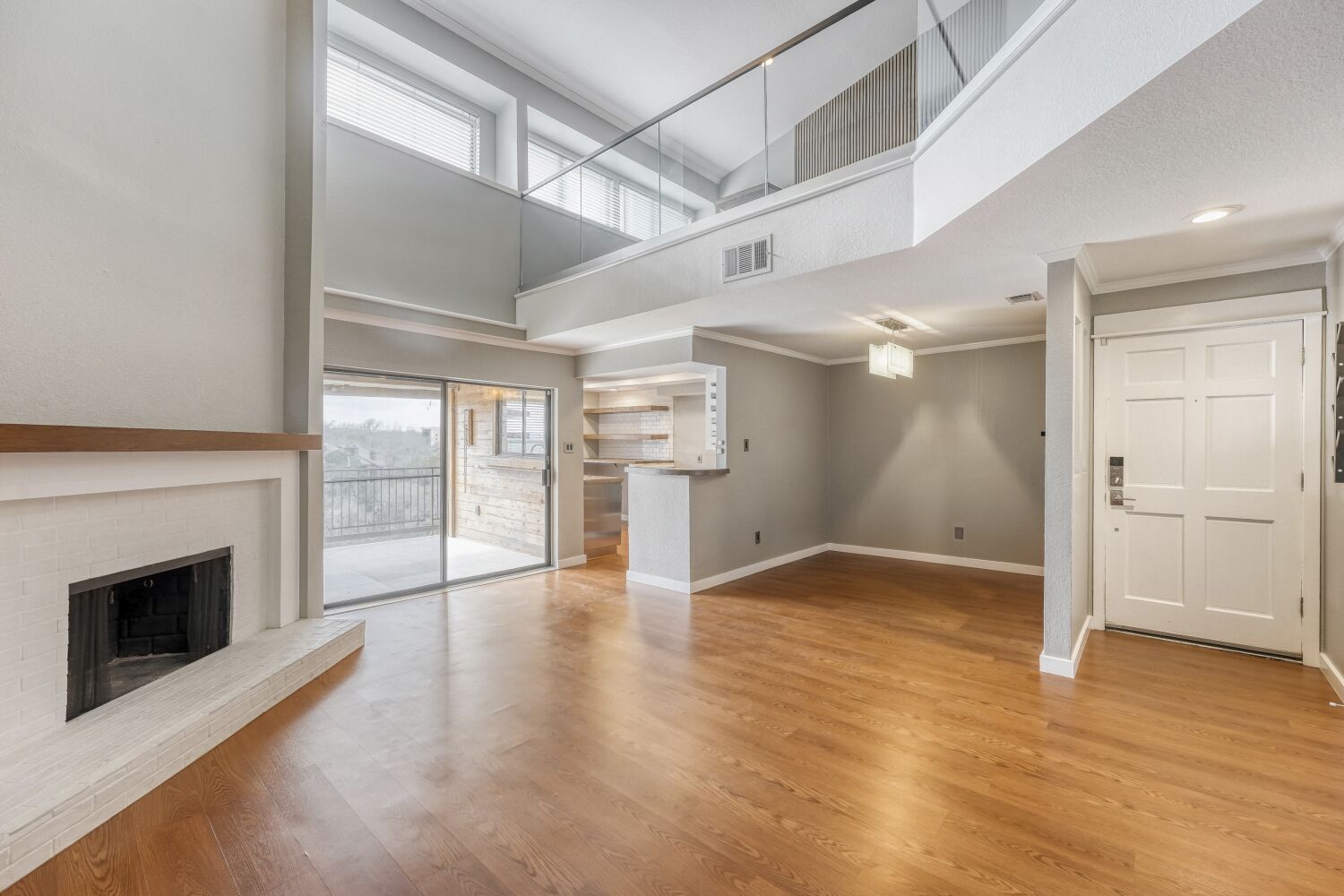 an empty room with wooden floor fireplace and windows