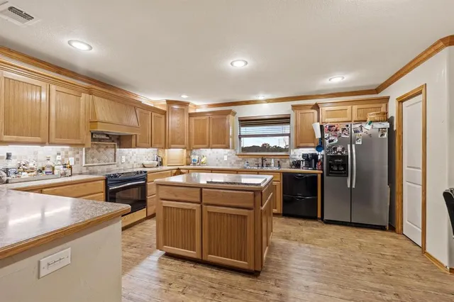 a kitchen with stainless steel appliances granite countertop a refrigerator a sink dishwasher a stove with wooden cabinets and floor