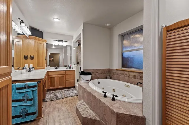 a bathroom with a bathtub a double vanity sink a vanity and a large mirror