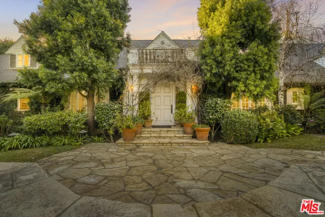 a view of a house with large trees and plants