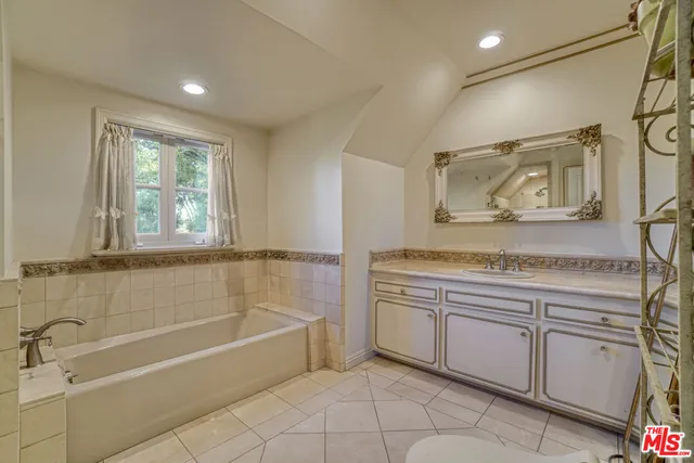 a spacious bathroom with a tub sink and mirror