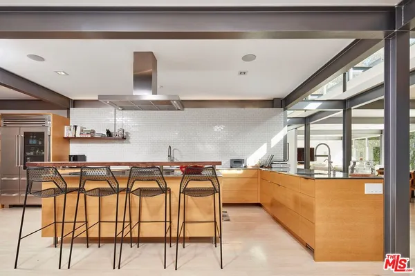 a kitchen with stainless steel appliances granite countertop a table chairs in it and wooden floors