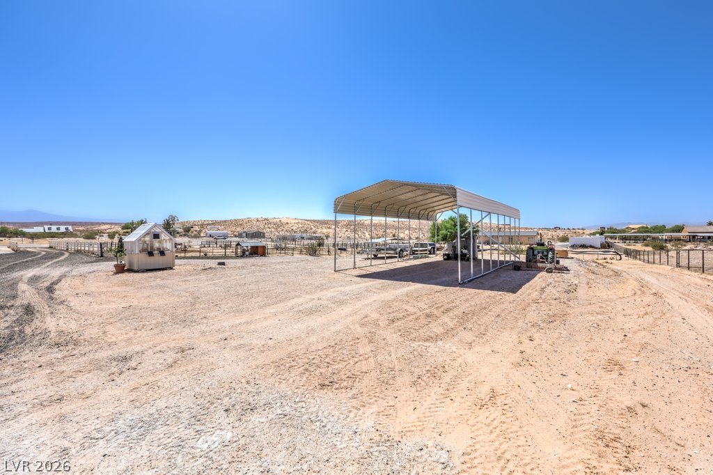 4375 Pinwheel Street Logandale, NV 89021 - Photo 39 of 52 A spacious desert lot offers ample room for vehicles, with a covered structure providing shade and protection.