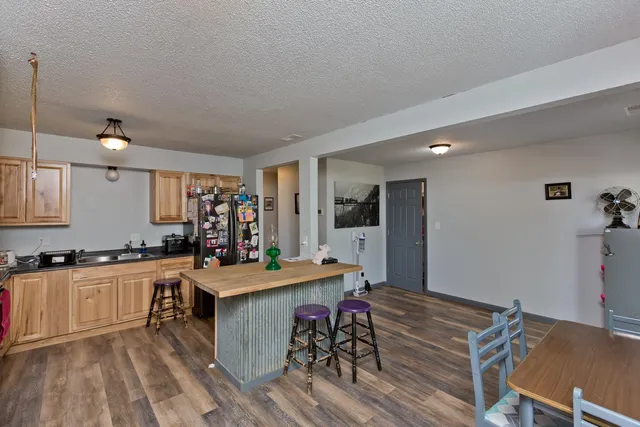 a kitchen with a stove a refrigerator a sink a dining table and chairs with wooden floor