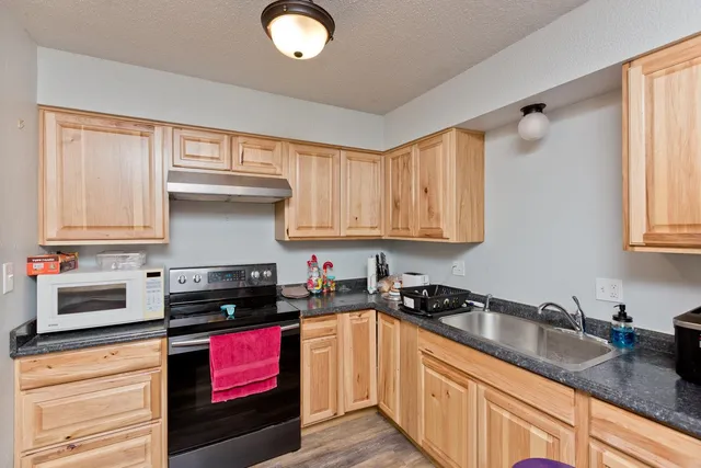 a kitchen with granite countertop a sink a stove and cabinets