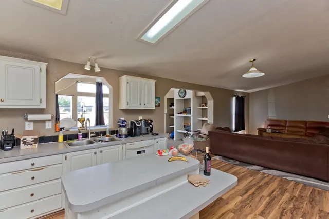 a kitchen with stainless steel appliances granite countertop a refrigerator a sink dishwasher and white cabinets with wooden floor