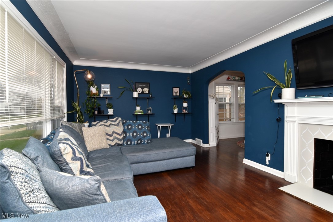 3921 Grosvenor Road Cleveland, OH 44118 - Photo 6 of 46 Living area with arched walkways, wood finished floors, and a fireplace with raised hearth