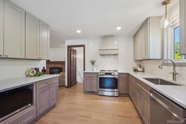 a kitchen with stainless steel appliances granite countertop a stove top oven a sink dishwasher and a refrigerator with wooden cabinets