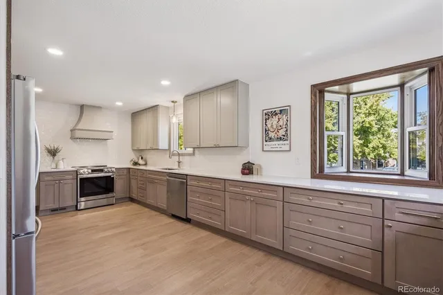 a kitchen with stainless steel appliances granite countertop a stove top oven a sink dishwasher and a refrigerator with wooden cabinets