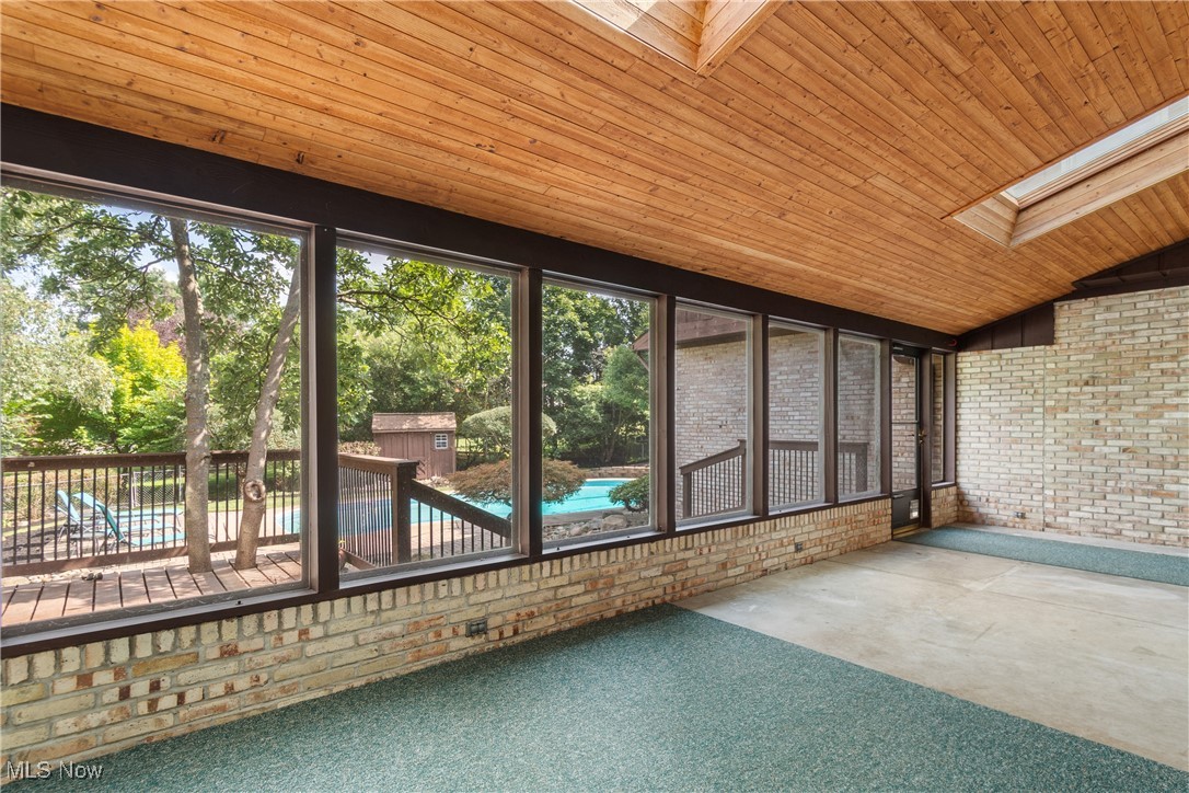 2317 Raintree Street Northeast Canton, OH 44705 - Photo 11 of 40 Unfurnished sunroom featuring brick wall, lofted ceiling, wood ceiling, carpet flooring, and a skylight