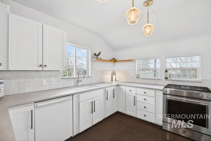 515 East D Street Moscow, ID 83843 - Photo 12 of 29 Kitchen featuring stainless steel gas range oven, white cabinets, white dishwasher, decorative backsplash, and light countertops
