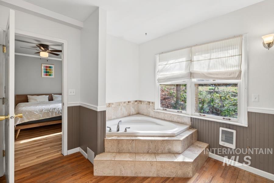 515 East D Street Moscow, ID 83843 - Photo 17 of 29 Ensuite bathroom with wood-type flooring, heating unit, a garden tub, a ceiling fan, and a wainscoted wall