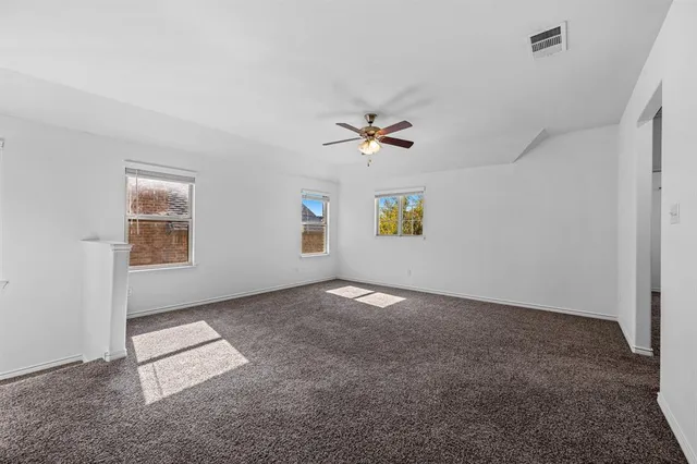 an empty room with windows and ceiling fan