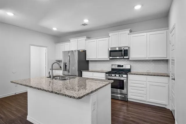 a kitchen with kitchen island granite countertop a stove and a sink