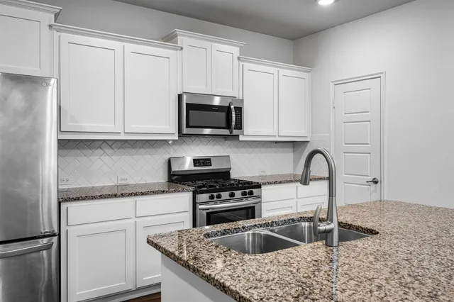 a kitchen with granite countertop a sink a stove and cabinets