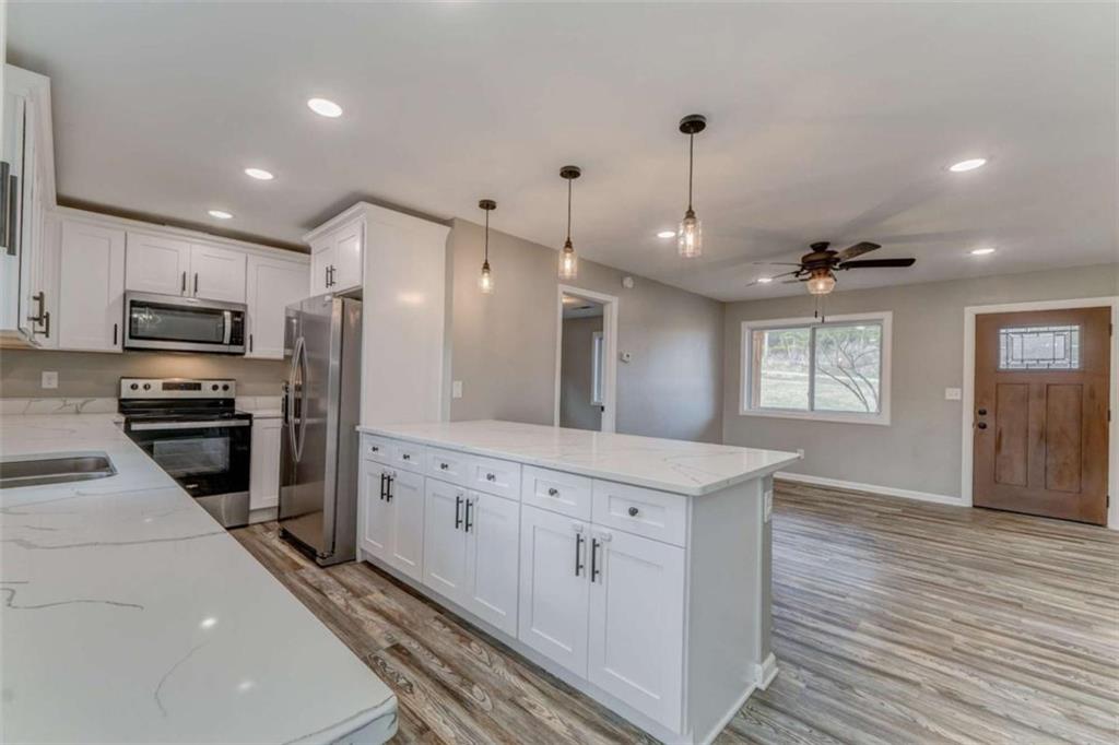 197 Colquitt Road Cedartown, GA 30125 - Photo 19 of 62 a kitchen with granite countertop a refrigerator oven a sink dishwasher and white cabinets with wooden floor