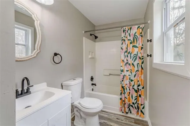 a bathroom with a granite countertop bathtub shower sink vanity and toilet