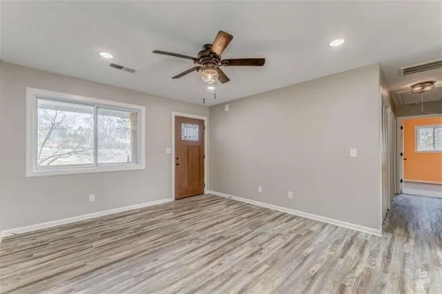 a view of empty room with wooden floor and fan