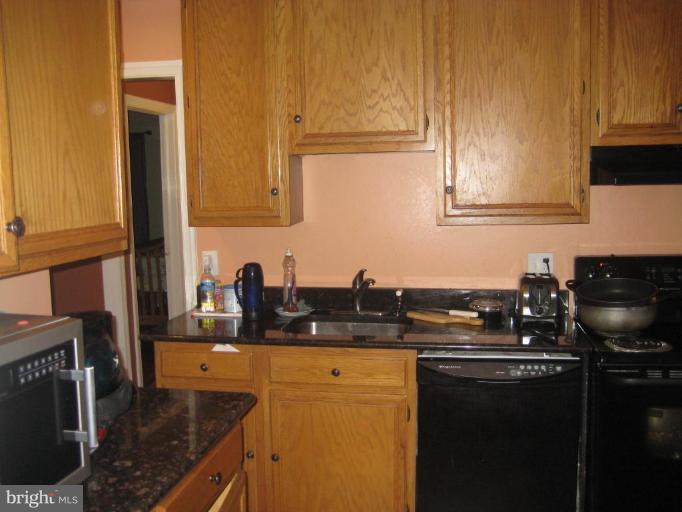 12310 Charles Road Silver Spring, MD 20906 - Photo 6 of 14 a kitchen with granite countertop a sink a stove and cabinets