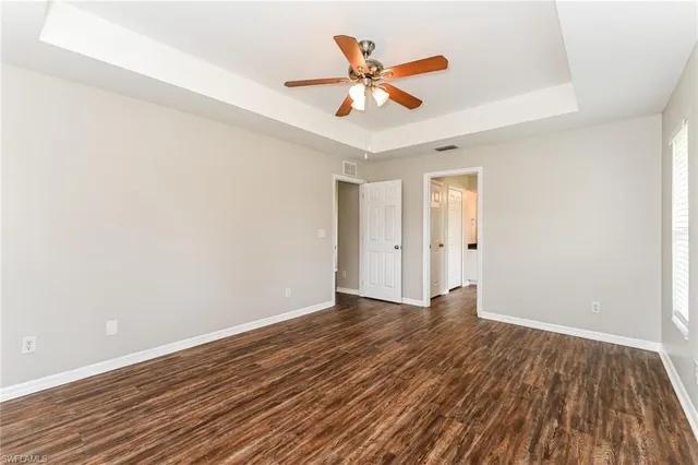an empty room with wooden floor and a ceiling fan