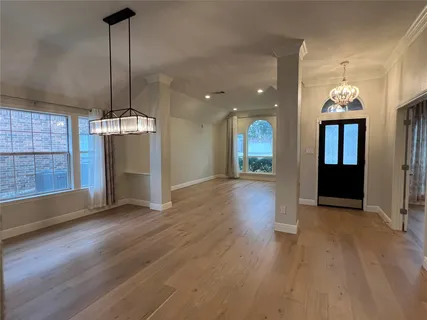 a view of empty room with wooden floor and kitchen view
