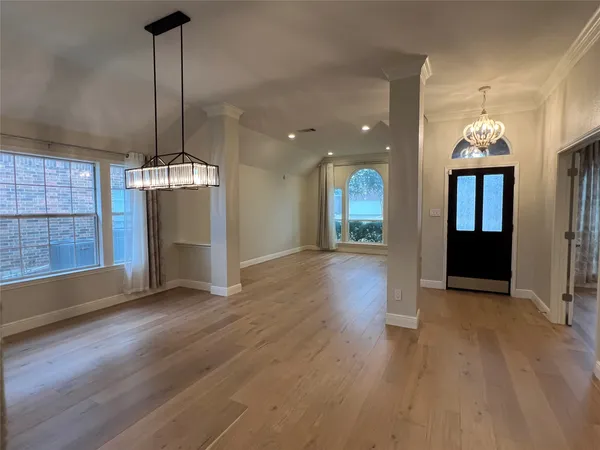a view of empty room with wooden floor and kitchen view
