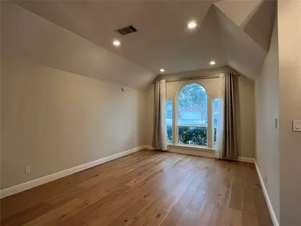an empty room with wooden floor and outdoor view