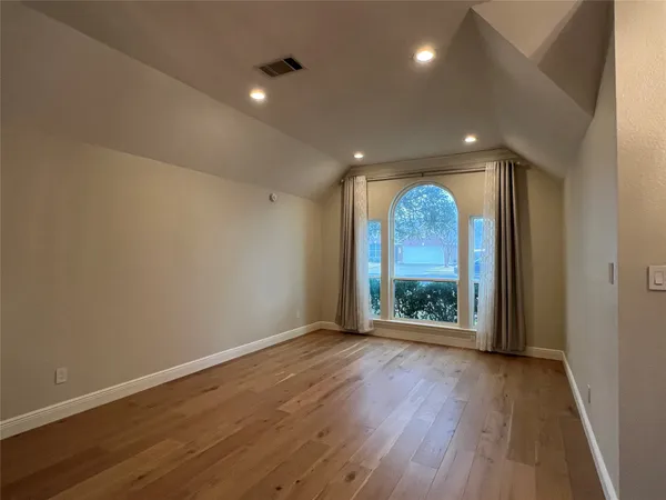 an empty room with wooden floor and outdoor view