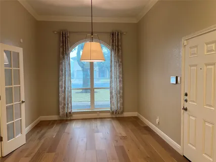 an empty room with wooden floor mirror and windows