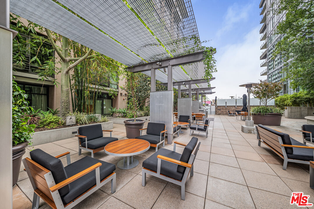 1100 South Hope Street, Unit 1501 Los Angeles, CA 90015 - Photo 51 of 63 a view of a patio with table and chairs potted plants and a large tree