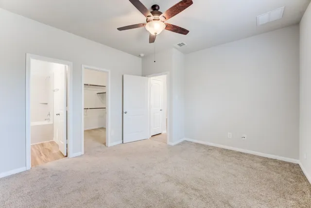an empty room with closet and a ceiling fan