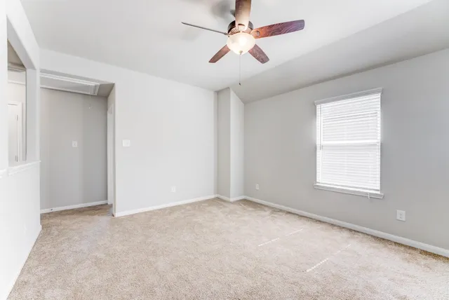 an empty room with a window and a fan