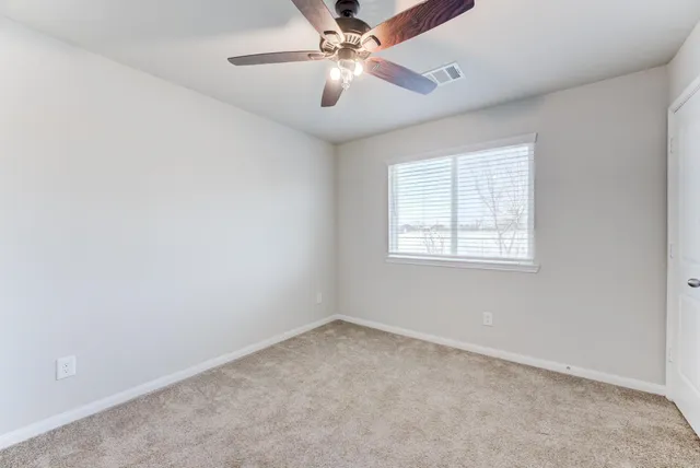 an empty room with a window and a ceiling fan
