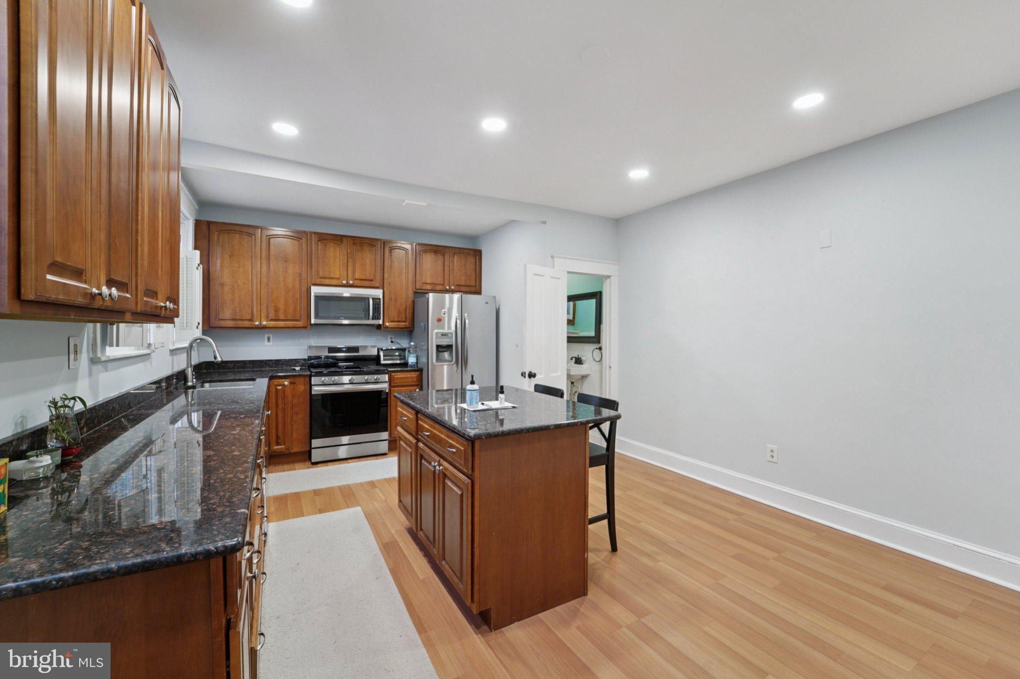 3929 Hudson Street Baltimore, MD 21224 - Photo 11 of 48 a kitchen with stainless steel appliances granite countertop wooden cabinets a sink dishwasher a stove and a refrigerator