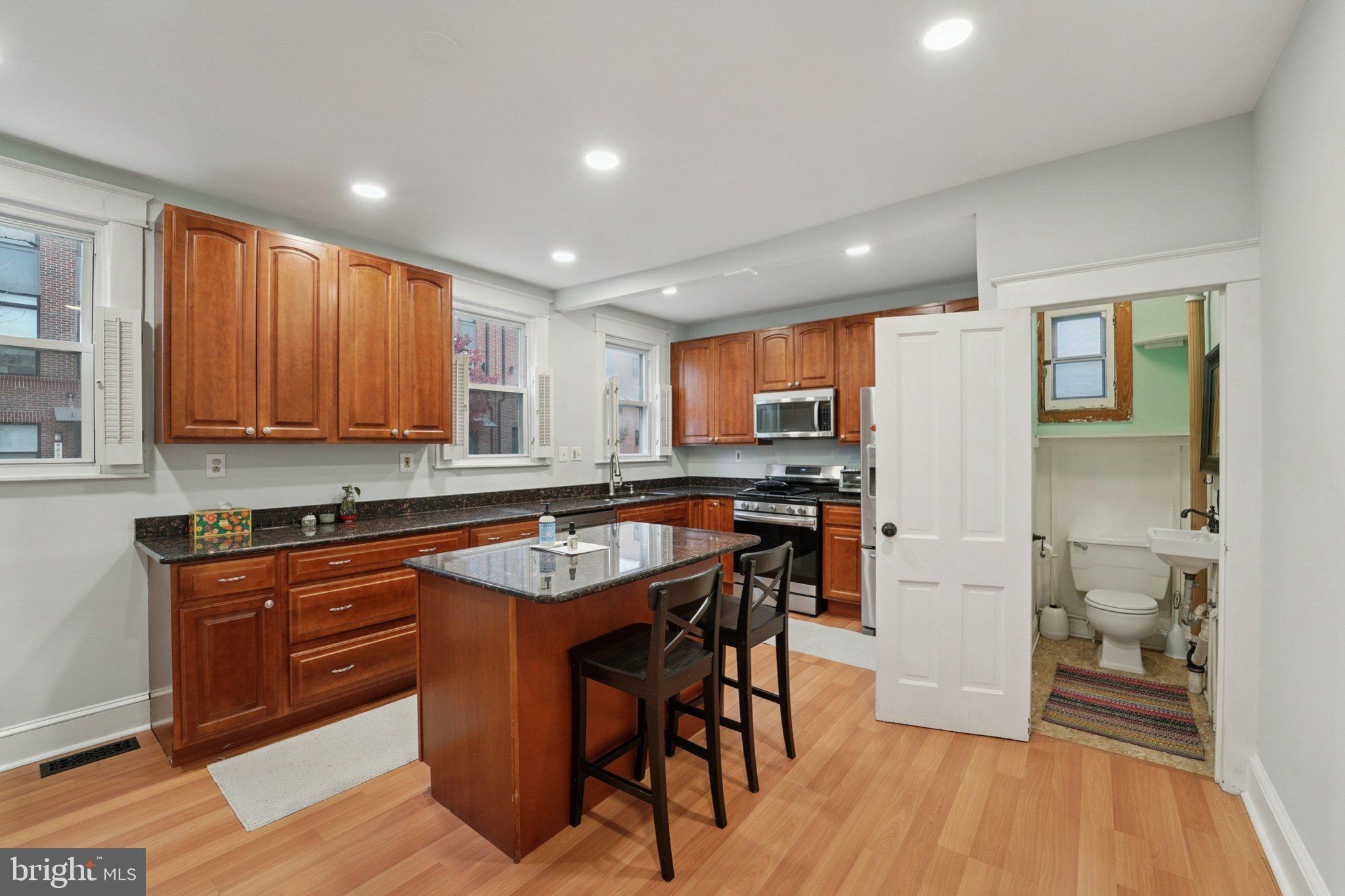3929 Hudson Street Baltimore, MD 21224 - Photo 12 of 48 a kitchen with stainless steel appliances granite countertop wooden floor window and cabinets
