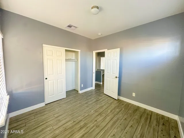 an empty room with wooden floor fan and windows
