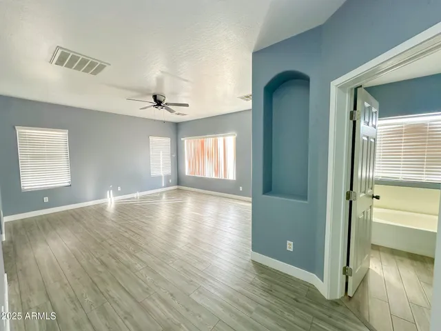 an empty room with wooden floor and windows