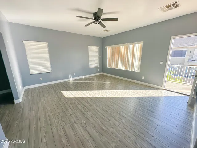 a view of empty room with wooden floor and fan