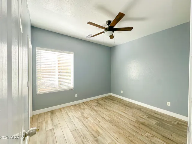 a view of empty room with wooden floor and ceiling fan