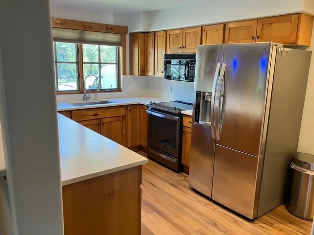 a kitchen with stainless steel appliances granite countertop a refrigerator a sink and a stove with wooden floors