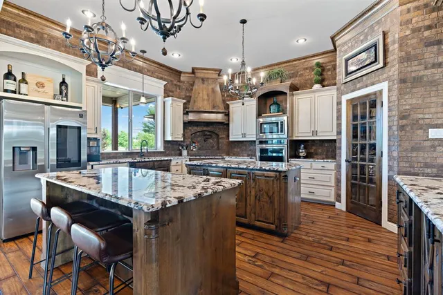 a kitchen with stainless steel appliances granite countertop a stove a refrigerator a oven a sink with a dining table and chairs