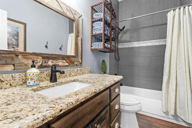 a bathroom with a granite countertop sink a toilet and shower
