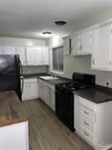 a kitchen with granite countertop a sink a stove a refrigerator and cabinets