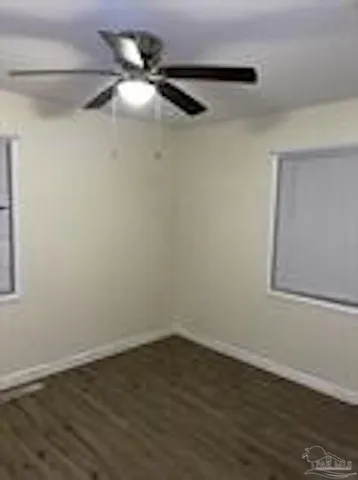 a view of a small space with wooden floor a fan and a window