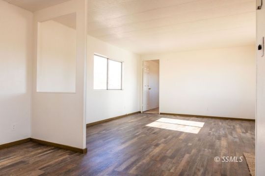 1249 North Charles Street Ridgecrest, CA 93555 - Photo 8 of 21 an empty room with wooden floor and windows