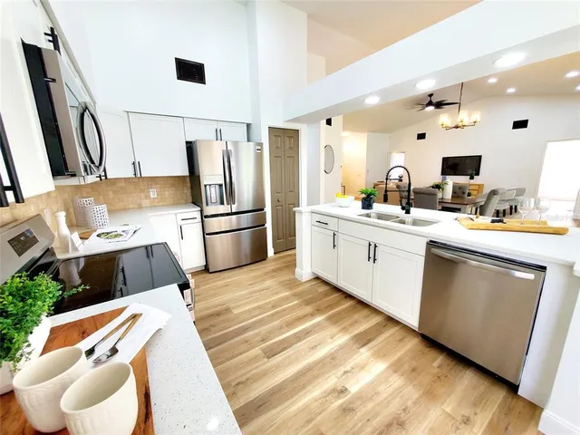 a kitchen with stainless steel appliances a sink a stove a refrigerator and cabinets