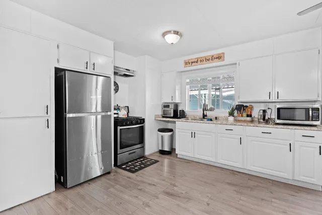 a kitchen with white cabinets stainless steel appliances and a window