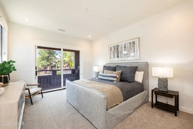 a bedroom with a bed and large windows