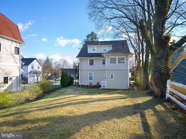a view of a house next to a big yard and large trees