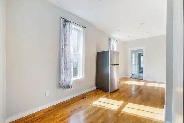 a view of empty room with wooden floor and fan